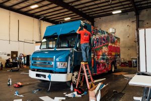 Trailer King Builders' employee painting and repairing food truck